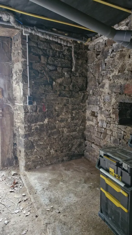 Local technique en préparation avec murs en pierre et réseaux apparents