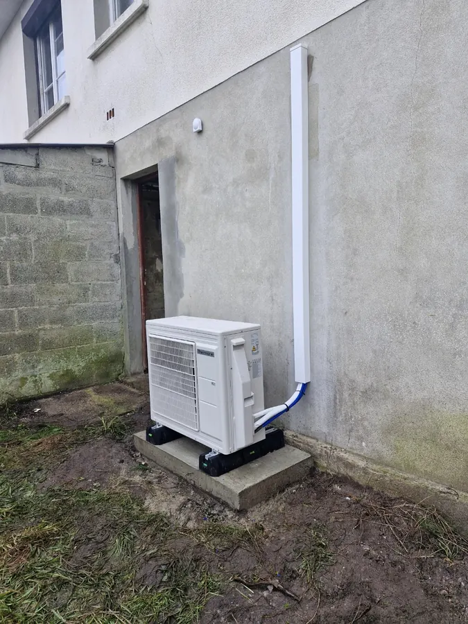 Unité extérieure de pompe à chaleur sur un support au pied d’une maison
