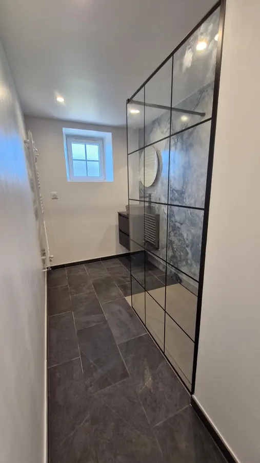 Salle de bains avec espace douche et paroi vitrée à montants noirs