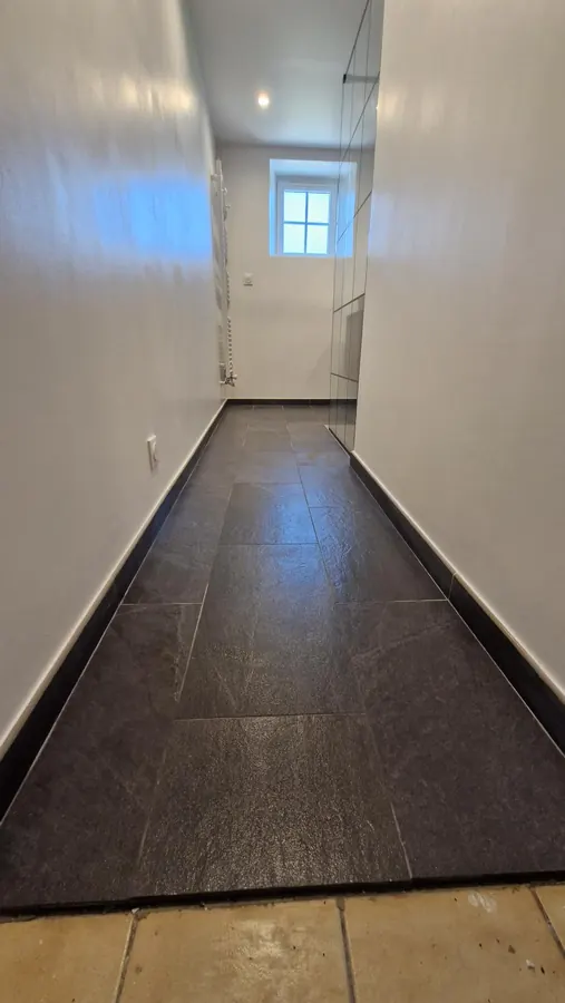 Salle de bains aménagée avec sol sombre, parois claires et fenêtre