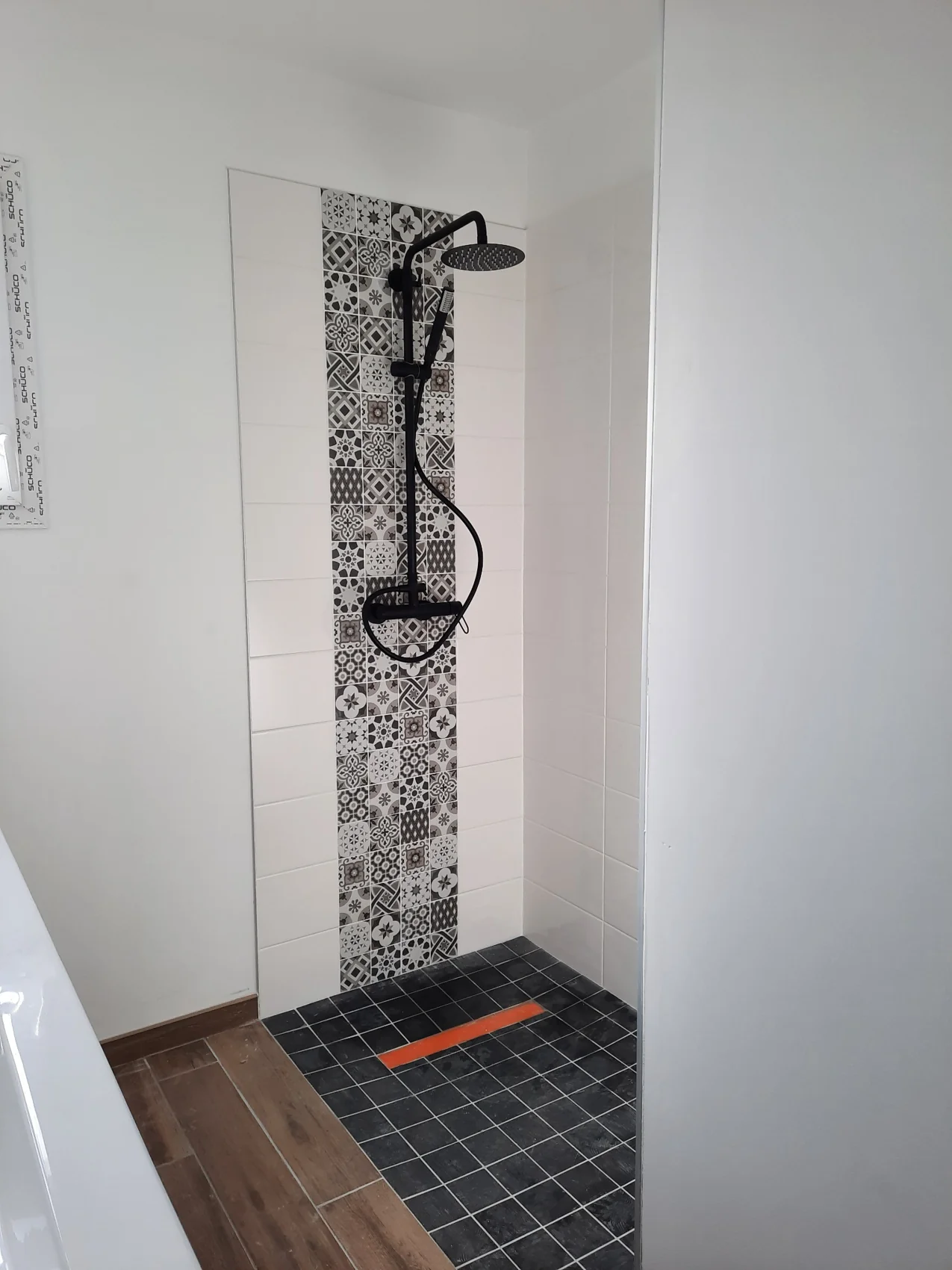 Douche carrelée avec colonne noire et frise à motifs
